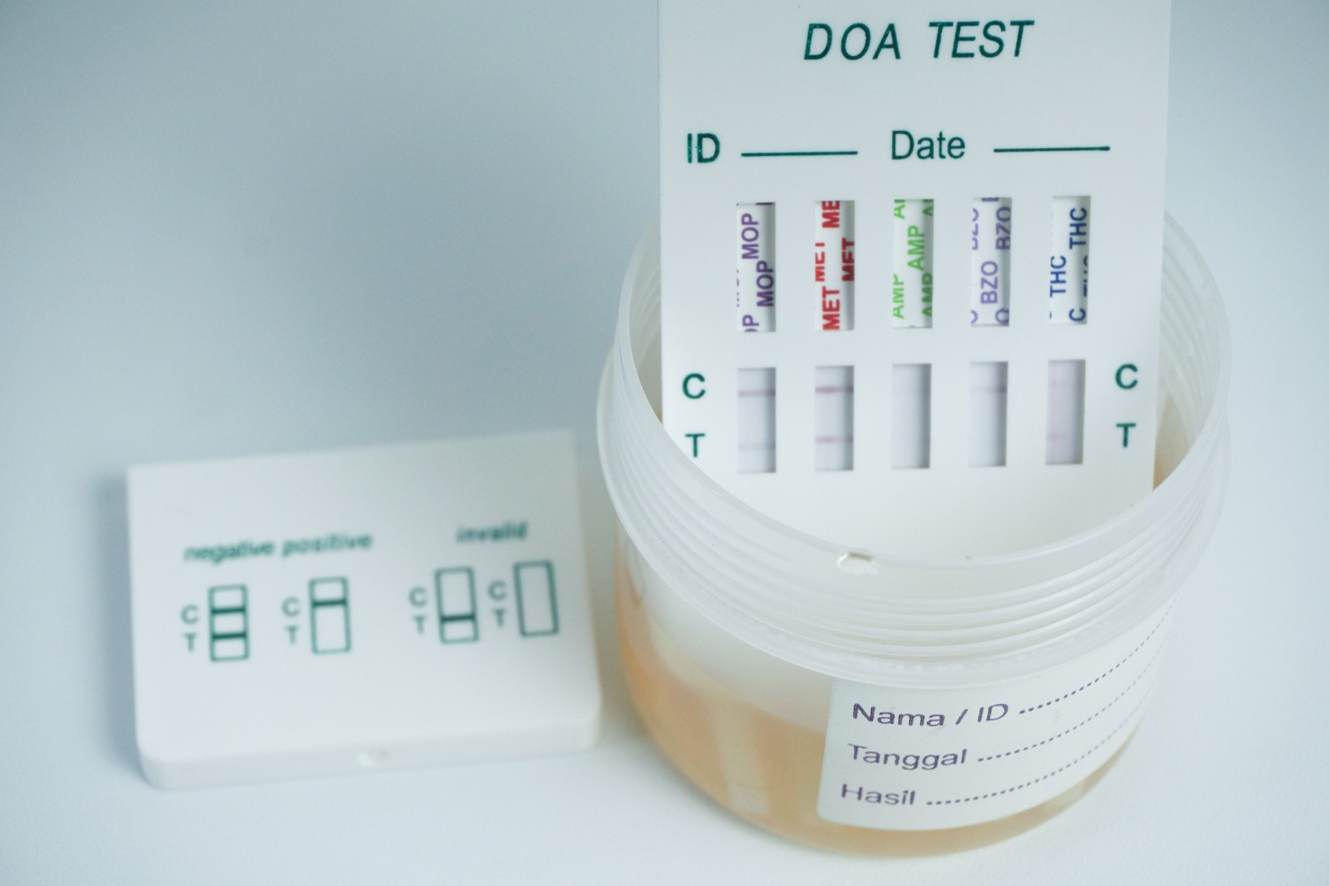 Examination of narcotic content in urine by placing the urine in a urine container and then immersing a portion of the drug test kit in the urine. isolated on white